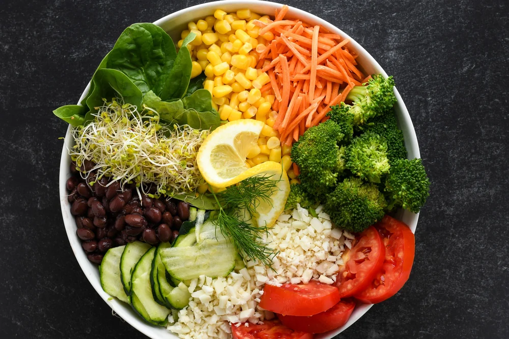 A bowl of vegetables, beans, corn and rice photographed from above